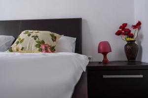 Una cama con una almohada y un jarrón de flores en una mesita de noche en OPIA Apartments - Old Town, en Bucarest