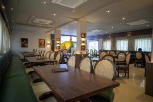 Tiger's Trail Hotel & Food Court في كمبالغره: مطعم بطاولات وكراسي خشبية وحارق طاولات