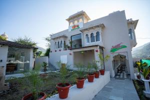 una casa blanca con plantas delante en Tiger's Trail Hotel & Food Court en Kumbhalgarh