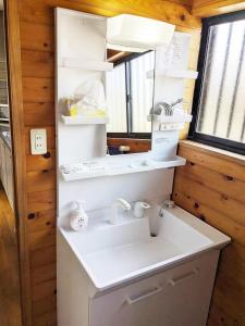 ein Bad mit einem Waschbecken und einem Spiegel in der Unterkunft シークレットベースゆふいん in Yufu