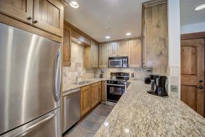 a kitchen with wooden cabinets and a stainless steel refrigerator at Resort Plaza 5012 by AvantStay Located in Park City Mountain Resort w Mountain Views in Park City