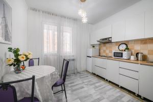 アルマトイにあるКак Дома -квартира в центреの白いキッチン(テーブル、電子レンジ付)