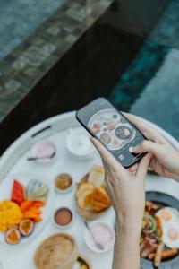 uma pessoa com um telemóvel na frente de um prato de comida em Arun Dara Villa em Chiang Mai