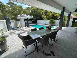 a patio with a table and chairs and a swimming pool at Private poolvilla Koh Lanta in Ko Lanta