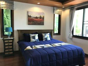 a blue bed in a bedroom with windows at Deluxe Pool Villa close to Beach and Walking Street! in Pattaya