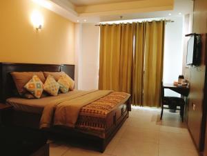 Schlafzimmer mit einem Bett, einem Schreibtisch und einem Fenster in der Unterkunft HOTEL CENTRA in Mohali
