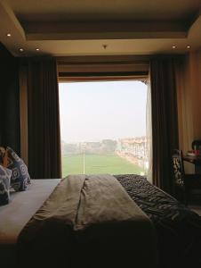 Schlafzimmer mit einem großen Fenster mit Blick auf ein Feld in der Unterkunft HOTEL CENTRA in Mohali