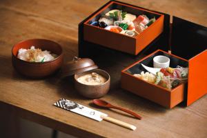 three boxes of food on a wooden table with chopsticks at Tsukihi House Kyoto in Kyoto