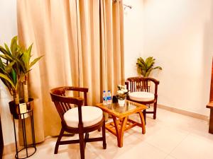 sala de estar con 2 sillas, mesa y cortina en Hotel Pacific Classic, Haridwar - A Four Star Luxury Hotel en Haridwār
