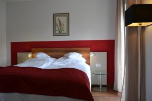 a bedroom with a red and white bed and a table at Hotel Vorderburg in Schlitz