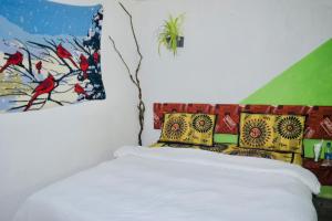 ein Schlafzimmer mit einem weißen Bett und bunten Kissen in der Unterkunft Pedro home stay in Nuwara Eliya