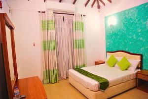 a bedroom with a bed with green pillows at Ared Villa in Katunayaka