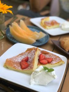 un plato blanco con un trozo de pastel con fresas. en Kebun Lisdtari farmstay en Air Hangat