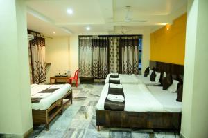 a room with four beds and a table and a chair at Hotel Sachidanand in Shirdi