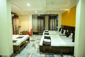 舍地Hotel Sachidanand-Walkable distance from Temple的一间设有四张床、一张桌子和一把椅子的房间