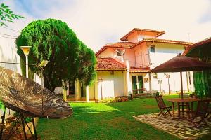 ein Haus mit einem Garten mit Stühlen und einem Sonnenschirm in der Unterkunft Ared Villa in Katunayaka