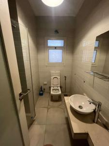 een badkamer met een toilet, een wastafel en een raam bij بالم هيلز ذا فيلج in Caïro