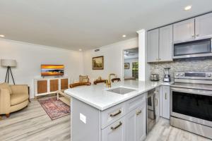 a kitchen with white cabinets and a living room at Le Malo Vacation Rental in Naples +12 photos