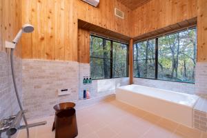 un bagno con vasca e una grande finestra di Ryojukukan Villa Nasukogen a Nasu