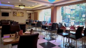 a restaurant with tables and chairs and a large window at Hotel Executive Tower in Kolkata