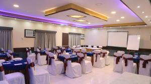 a conference room with tables and chairs and a screen at Hotel Executive Tower in Kolkata
