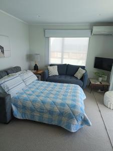 a bedroom with a bed and a couch at Omanu Cottage in Mount Maunganui
