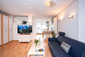 sala de estar con sofá azul y TV en Fewo Strandkrabbe, en Grömitz