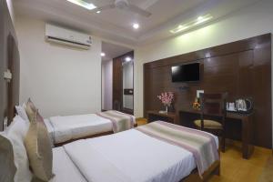 ein Hotelzimmer mit 2 Betten und einem TV in der Unterkunft Hotel Haris MG Road Gurugram in Gurgaon