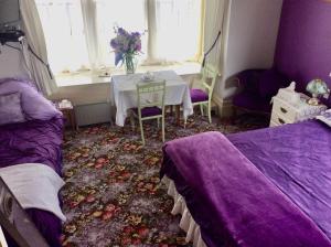 a bedroom with two beds and a table with a vase of flowers at Catlins Retreat B & B in Owaka