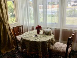a table with a vase of flowers on it in a room with windows at Catlins Retreat B & B in Owaka