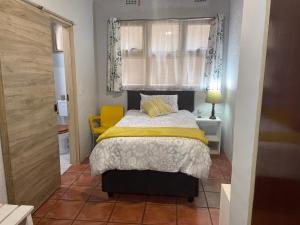 um pequeno quarto com uma cama e uma cadeira amarela em Sabie Stay em Sabie