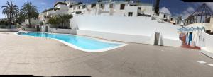 a swimming pool in front of a white building at Isis House in Maspalomas
