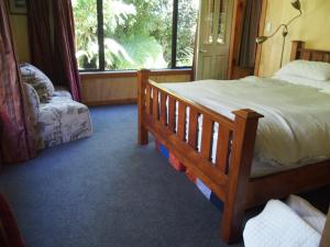 a bedroom with a bed and a chair and a window at Woodland eco retreat in Parapara 