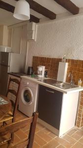 een keuken met een wasmachine en een wastafel bij Appartement médiéval au cœur du village de Lama in Lama