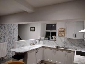 a white kitchen with a sink and a counter at Lavender Cottage, Masham, Historic Listed, 2 bedrooms in Masham