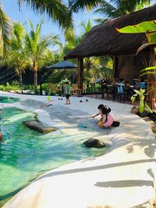 a group of people playing with seals in the water at a resort at Cóc Retreat Mỹ Tho City in My Tho