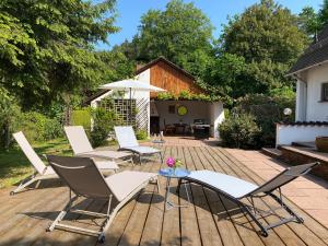 einer Gruppe von Stühlen und einem Regenschirm auf einer Terrasse in der Unterkunft Messe- & Ferienhaus Gertraud am Ludwigskanal in Wendelstein