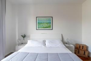 a white bed in a white bedroom with a picture on the wall at LA MAR Apartment Spinea in Spinea