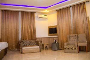 a hotel room with a bed and a chair and a tv at Emperor Melanie Hotels in Akwa