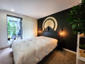1 dormitorio con 1 cama blanca grande y pared negra en RIVERSIDE OASIS station-parking-riverboat, en Woolwich