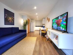 sala de estar con sofá azul y TV de pantalla plana en RIVERSIDE OASIS station-parking-riverboat, en Woolwich