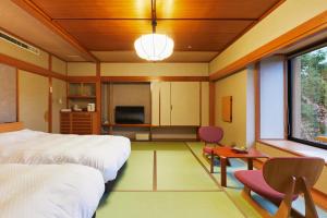 1 dormitorio con cama, mesa y TV en Takinoyu Hotel, en Tendō