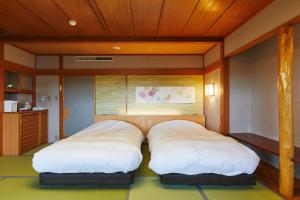 two beds sitting in a room with at Takinoyu Hotel in Tendo