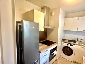 een keuken met een koelkast en een wasmachine bij Le Sept avec parking, transfert in Vaires-sur-Marne