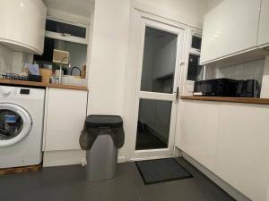 uma cozinha com uma máquina de lavar roupa e uma janela em Tooting Lodge London - Cosy 2 bedroom house with garden em Londres