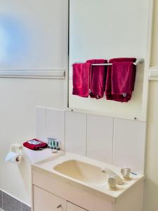 a white bathroom with a sink and red towels at country way motor inn in Cunnamulla