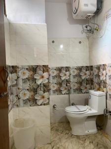 a bathroom with a toilet and flowers on the wall at Purnima Guest House, Old Kasol in Kasol