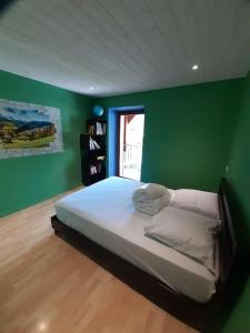 1 dormitorio con 1 cama en una pared verde en Maison Cosy, cœur de village en École