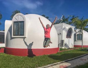 a woman jumping in the air in front of a house at The Lion Kingdom Sigiriya in Sigiriya