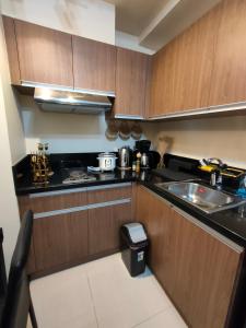 a small kitchen with wooden cabinets and a sink at Radiance Manila bay near CCP, PICC Pasay in Manila